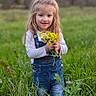 casual_clothing, child, cute, daylight, denim_overalls, field, flowers, girl, grass, green, long_hair, nature, outdoor, plants, portrait, scenery, smile, standing, yellow, young
