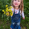 blonde_hair, blue_eyes, casual_clothing, child, cute, daylight, denim_overalls, field, flowers, girl, grass, greenery, happy, long_sleeve_shirt, nature, outdoor, portrait, smiling, spring, yellow_flowers