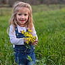 Oakley Young joined the competition — help win amazing prizes! blonde_hair, child, cute, denim_overalls, field, flower, girl, green_grass, happy, holding, long_sleeve_shirt, nature, outdoor, plants, portrait, scenery, smiling, standing, yellow_flower, young