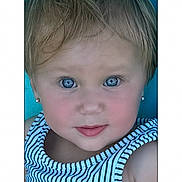 Jillian is registered to the contest to win money with this photo: blue_eyes, child, close_up, date_display, digital_interface, earrings, expression, face, head_and_shoulders, indoors, light_hair, looking_at_camera, person, phone_screen, portrait, skin, sleeveless_top, striped_clothing, time_display, young_child