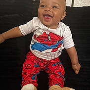Jaylen joined the competition — help win amazing prizes! baby, child, smiling, happy, spiderman, pajamas, sitting, couch, indoor, toddler, clothing, face, person, footwear, sock, cute, joyful, portrait, infant, black_background