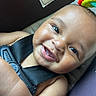 baby, smiling, face, child, car_seat, safety_harness, teeth, skin, closeup, happy, infant, toy, colorful, seat, seatbelt, cute, portrait, expression, human, baby_toy