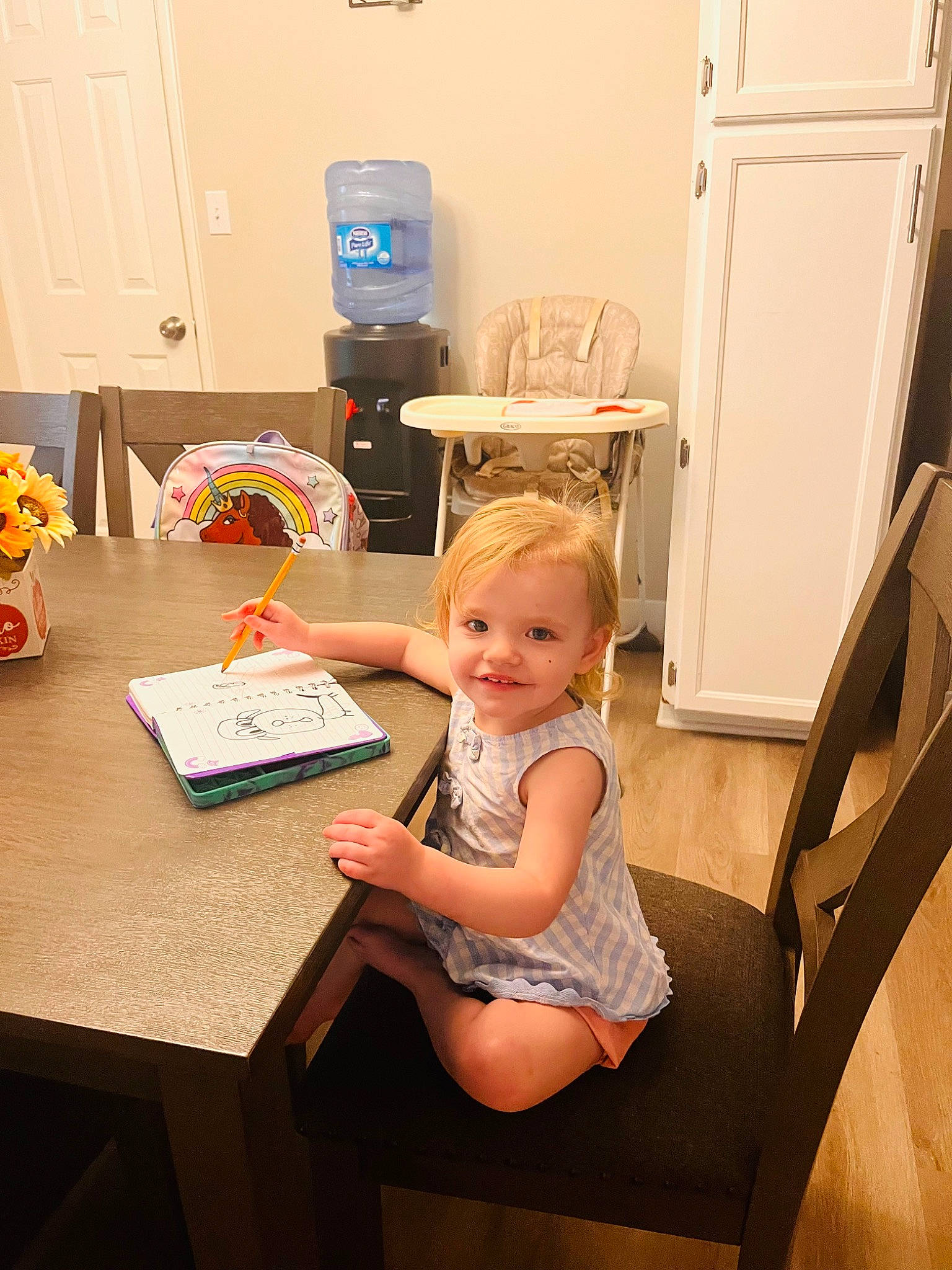 Dallas is registered to the contest to win money with this photo: cabinetry, chair, child, desk, door, drawer, event, flooring, fun, home_appliance, joy, kitchen_appliance, person, refrigerator, room, sitting, smile, table, thigh, toddler