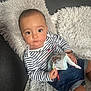 baby, book, child, couch, cozy, cute, denim_shorts, face, fluffy, hand, home, indoor, monkey, person, pillow, portrait, sitting, soft_lighting, striped_shirt, young