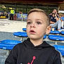 Matia a rejoint le concours — aidez-le/la à gagner de superbes lots ! audience, blue_seats, boy, candid, casual_clothing, child, curious, daylight, event, expression, hoodie, outdoor, people, portrait, public, seating, spectator, sports, stadium, young