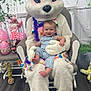 baby, child, mascot, easter_bunny, costume, chair, indoor, decoration, flowers, eggs, holiday, spring, smiling, person, plush, toy, floor, happy, festival, cute