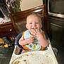 River joined the competition — help win amazing prizes! baby, high_chair, messy, food, smiling, kitchen, bib, fingers, happy, indoor, table, flower_vase, microwave, cabinet, wooden_chair, floor, person, child, home, feeding
