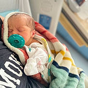 Stevie is registered to the contest to win money with this photo: newborn, baby, sleeping, pacifier, blanket, striped_blanket, hospital, person, clothing, closeup, rest, comfort, infant, soft_texture, care, head, face, peaceful, indoor, portrait