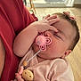 Giulia a rejoint le concours — aidez-le/la à gagner de superbes lots ! baby, sleeping, pacifier, pink, bow, hand, infant, clothing, fabric, indoor, person, child, cute, soft, skin, wooden_beads, holding, comfort, rest, closeup
