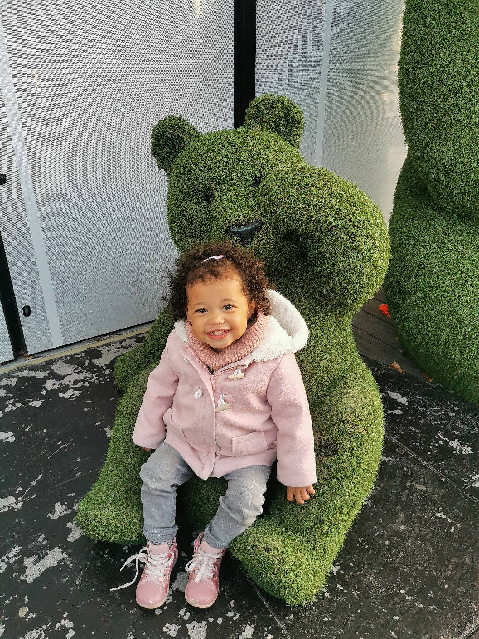 Thayna participe au concours pour gagner de l'argent avec cette photo : baby, baby_toddler_clothing, child, comfort, door, flooring, fun, fur, grass, green, happy, hedge, human_body, joy, person, plant, plush, sleeve, smile, stuffed_toy