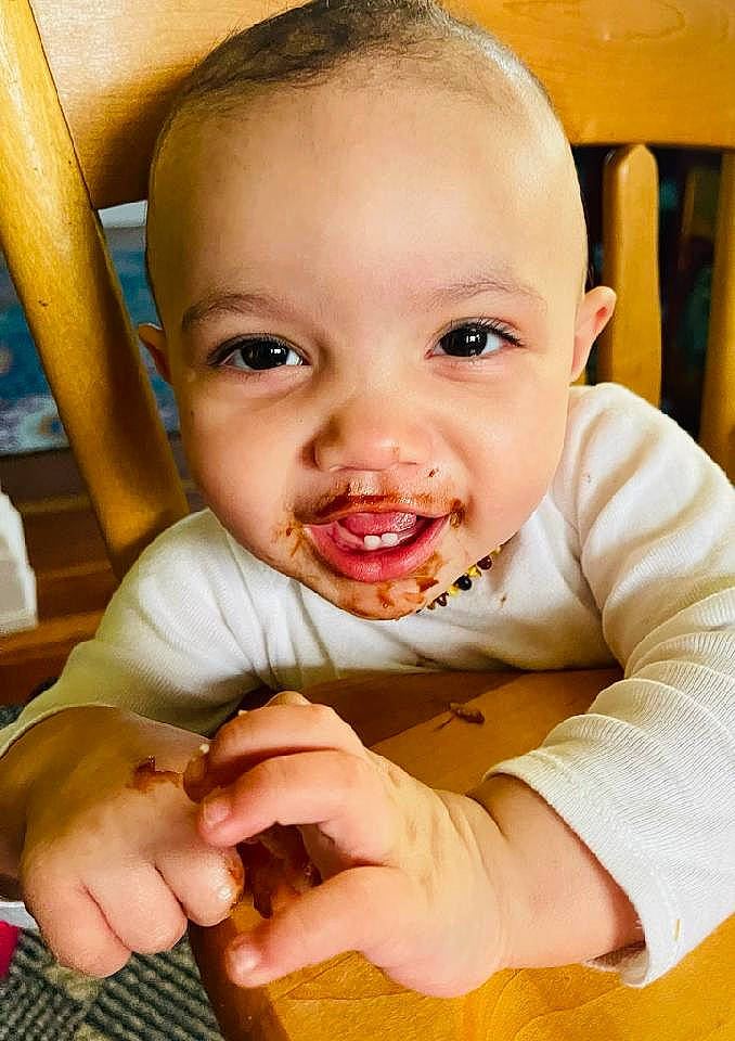Nova is registered to the contest to win money with this photo: baby_playing_with_food, cheek, dress, eye, finger, food, food_craving, gesture, hair, hand, happy, human_body, iris, lip, mouth, nose, orange, person, skin, standing