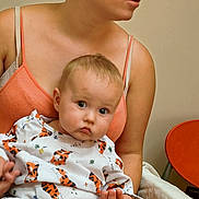 Braydon is registered to the contest to win money with this photo: baby, child, woman, person, indoor, clothing, pattern, tiger_print, holding, seated, skin, face, head, earring, expression, candid, portrait, adult, hand, orange