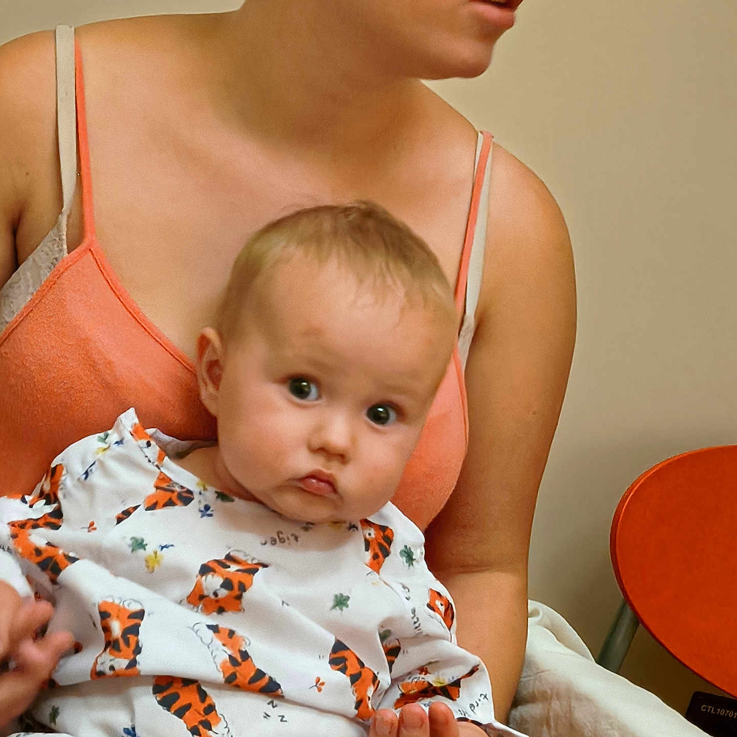 Braydon is registered to the contest to win money with this photo: baby, child, woman, person, indoor, clothing, pattern, tiger_print, holding, seated, skin, face, head, earring, expression, candid, portrait, adult, hand, orange