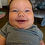 baby, smiling, face, chubby_cheeks, striped_shirt, indoor, child, happy, close_up, person, cute, young_child, head, expression, portrait, seated, furniture, floor, clothing, skin
