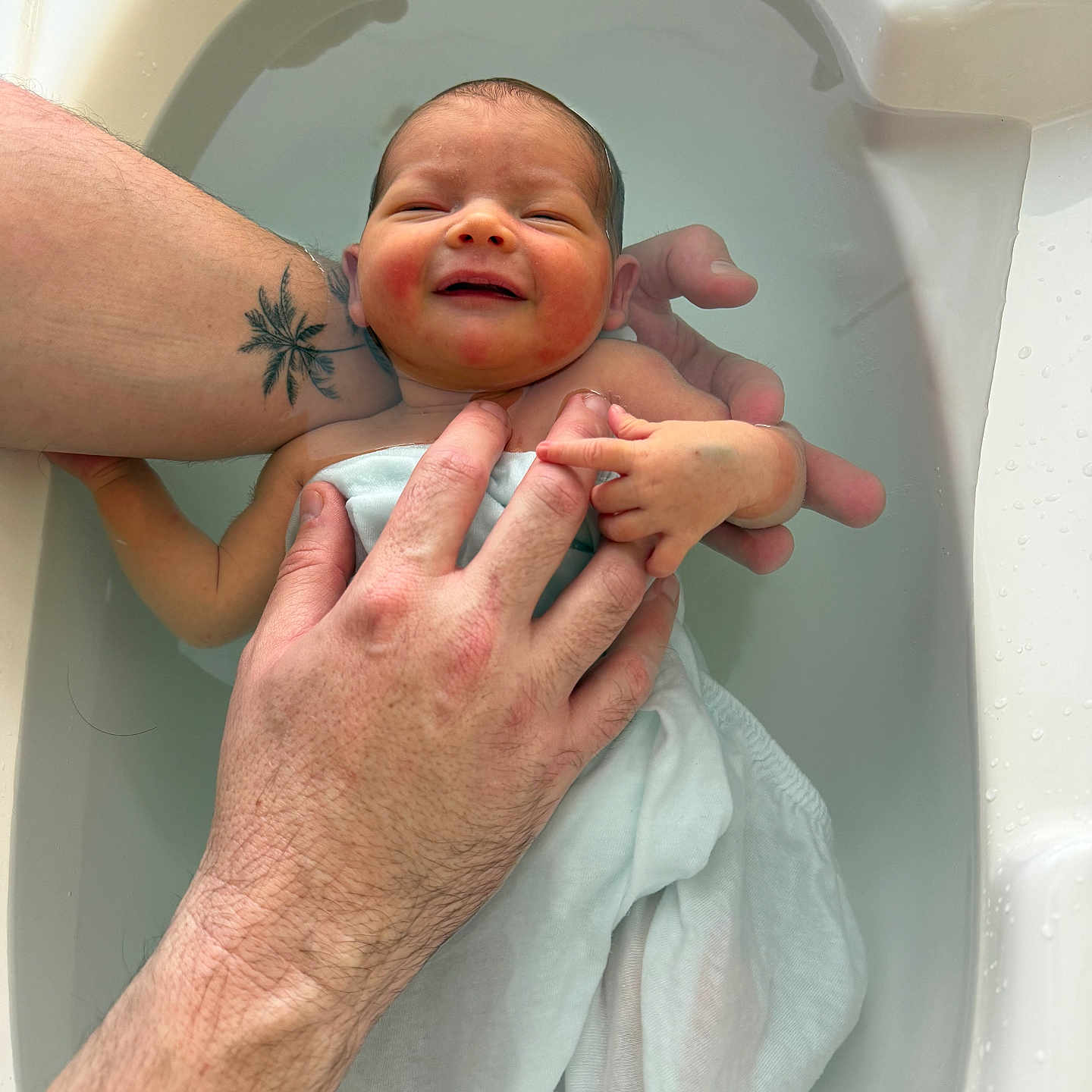 Alba a rejoint le concours — aidez-le/la à gagner de superbes lots ! newborn, baby, infant, bath, water, hands, tattoo, skin, smile, white_cloth, bathtub, relaxation, parental_care, human, baby_skin, closeup, gentle, cleaning, child, toddler