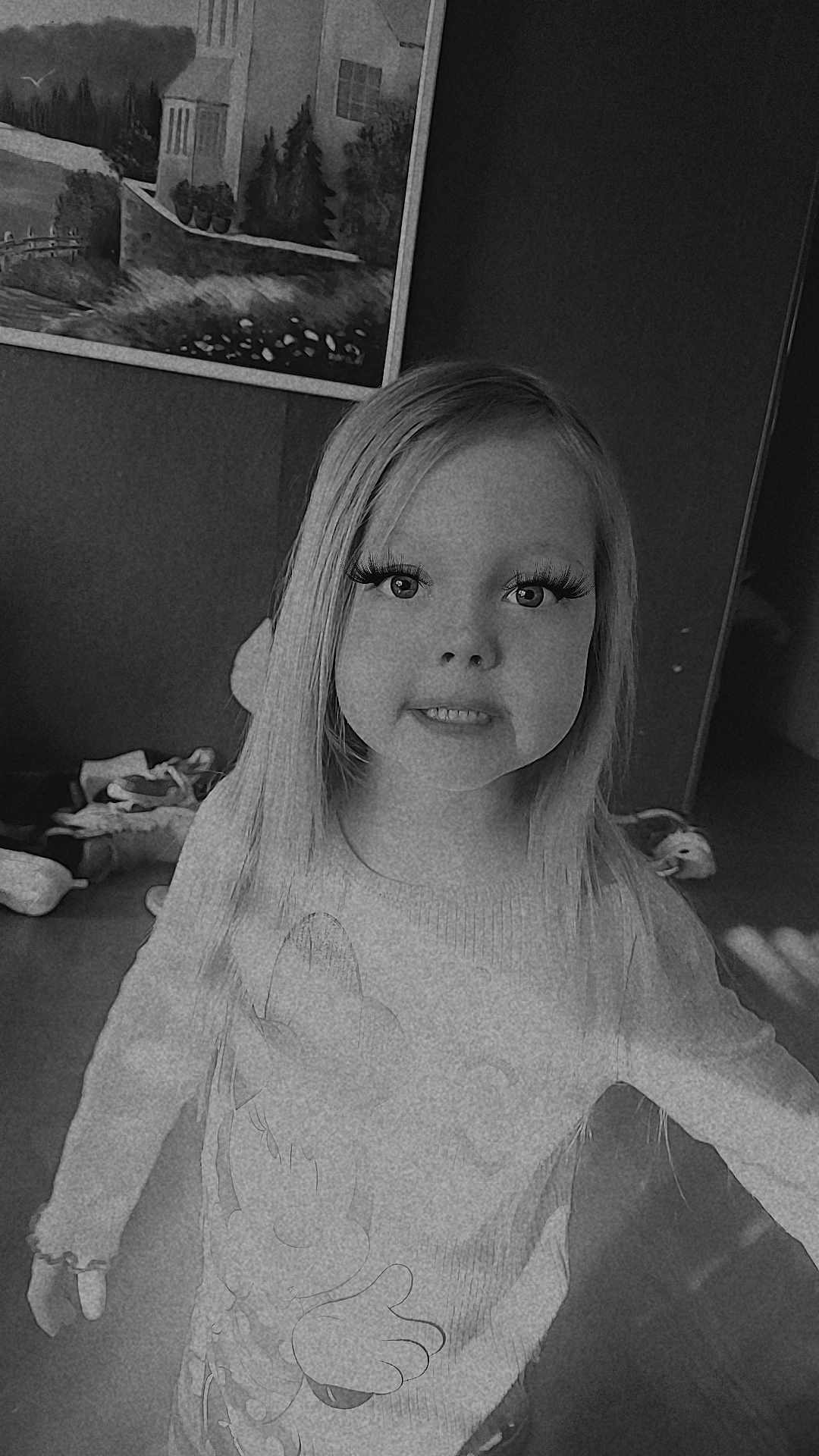 Taegan joined the competition — help win amazing prizes! child, girl, smile, long_hair, fake_eyelashes, sweater, character_sweater, indoor, portrait, black_and_white, grainy_filter, teeth, eyes, painting_on_wall, toys, floor, standing, young_kid, hair, camera_pose