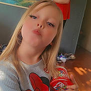 Taegan is registered to the contest to win money with this photo: child, girl, blond_hair, long_hair, sweater, minnie_mouse, cartoon, cereal_tub, froot_loops, holding, portrait, indoor, man, adult, painting, living_room, sunlight, filter, selfie_style, playful