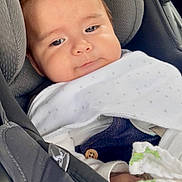 Santiago joined the competition — help win amazing prizes! baby, car_seat, blanket, child, infant, face, person, clothing, seatbelt, car_interior, cute, young, head, smile, comfort, travel, safety, resting, indoors, portrait