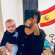 Naïmen a rejoint le concours — aidez-le/la à gagner de superbes lots ! baby, child, person, indoor, selfie, phone, mirror, clothing, flag, spanish_flag, curtain, bed, blanket, smile, hand, hair, room, furniture, casual, holding
