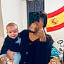 baby, child, person, indoor, selfie, phone, mirror, clothing, flag, spanish_flag, curtain, bed, blanket, smile, hand, hair, room, furniture, casual, holding