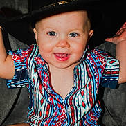 Harlan joined the competition — help win amazing prizes! baby, child, smiling, blue_eyes, colorful_shirt, patterned_clothing, cowboy_hat, hat, happy, portrait, sitting, indoor, cute, infant, face, person, young_child, fashion, closeup, playful