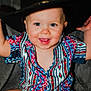 baby, child, smiling, blue_eyes, colorful_shirt, patterned_clothing, cowboy_hat, hat, happy, portrait, sitting, indoor, cute, infant, face, person, young_child, fashion, closeup, playful