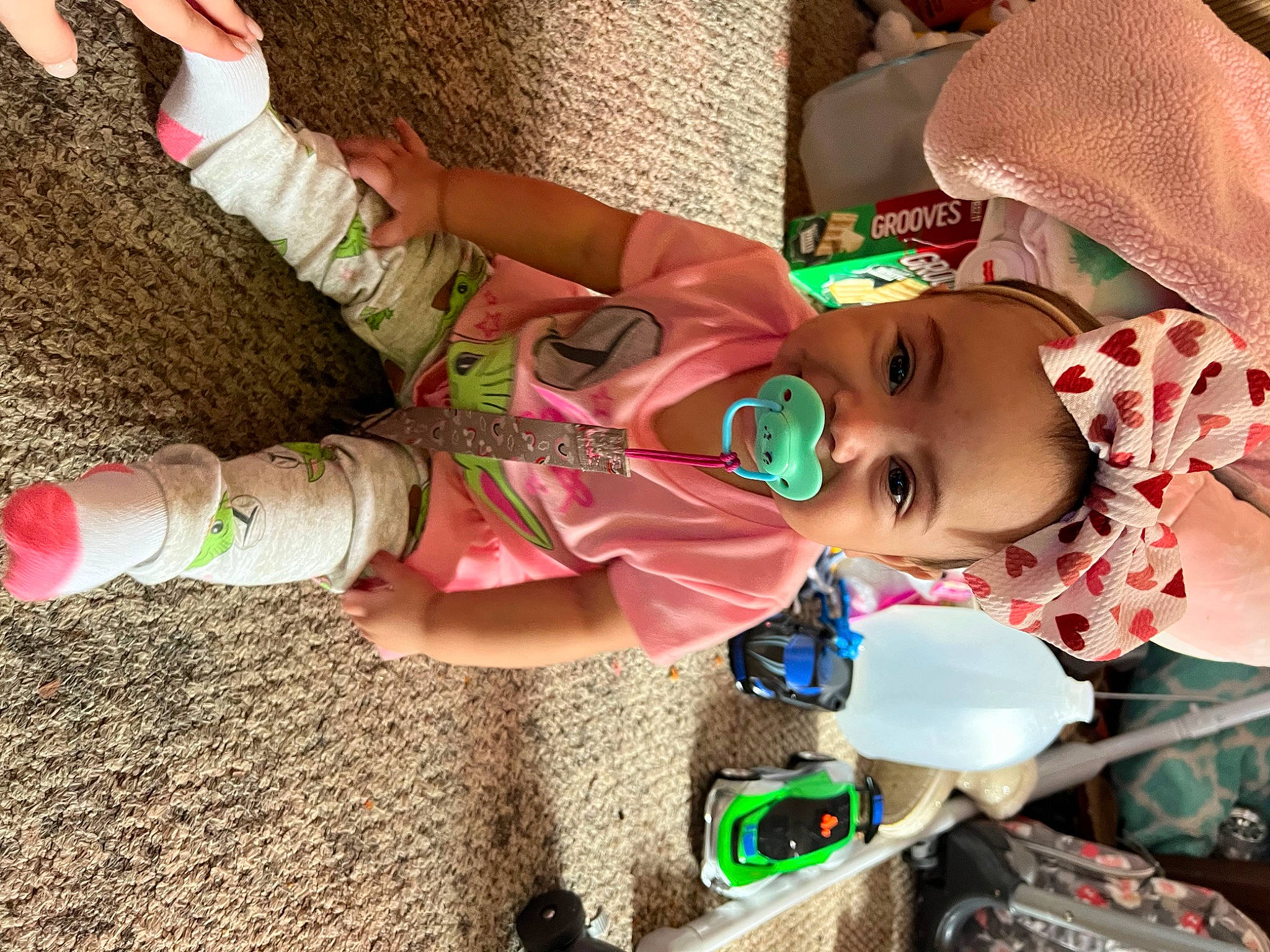 Allie is registered to the contest to win money with this photo: baby, baby_products, baby_toddler_clothing, child, event, fun, green, happy, hat, human_body, human_leg, knee, pattern, people_in_nature, person, play, smile, sock, soil, thigh