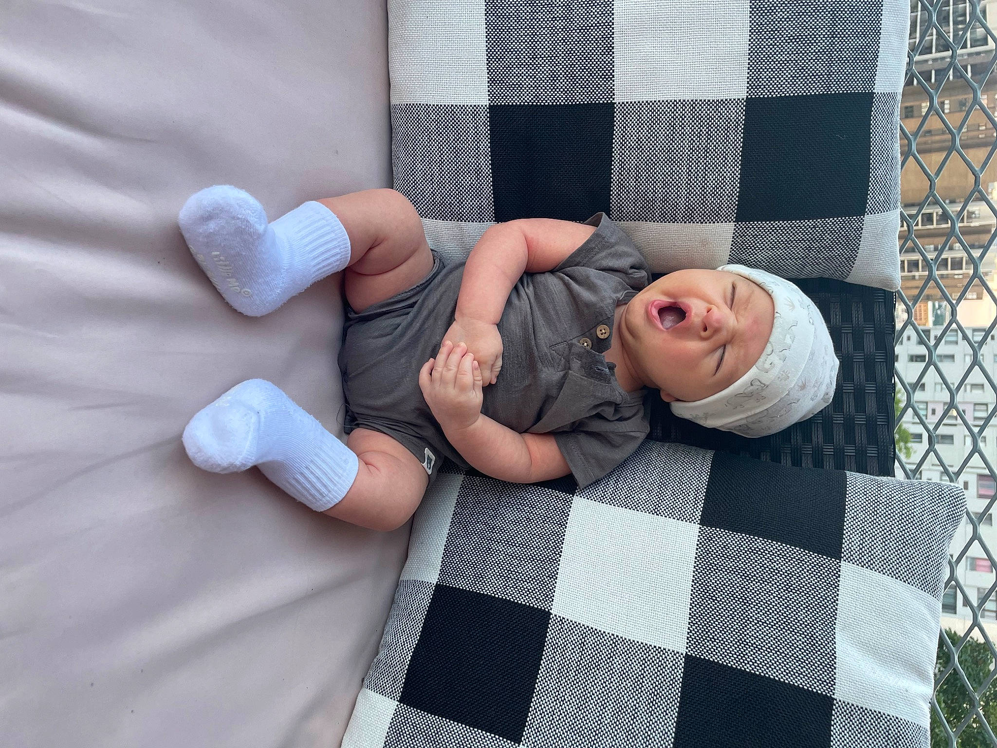 Nico joined the competition — help win amazing prizes! bedding, child, comfort, finger, floor, flooring, foot, gesture, headwear, human_leg, knee, linens, pattern, person, plaid, sitting, sock, tartan, textile, thumb
