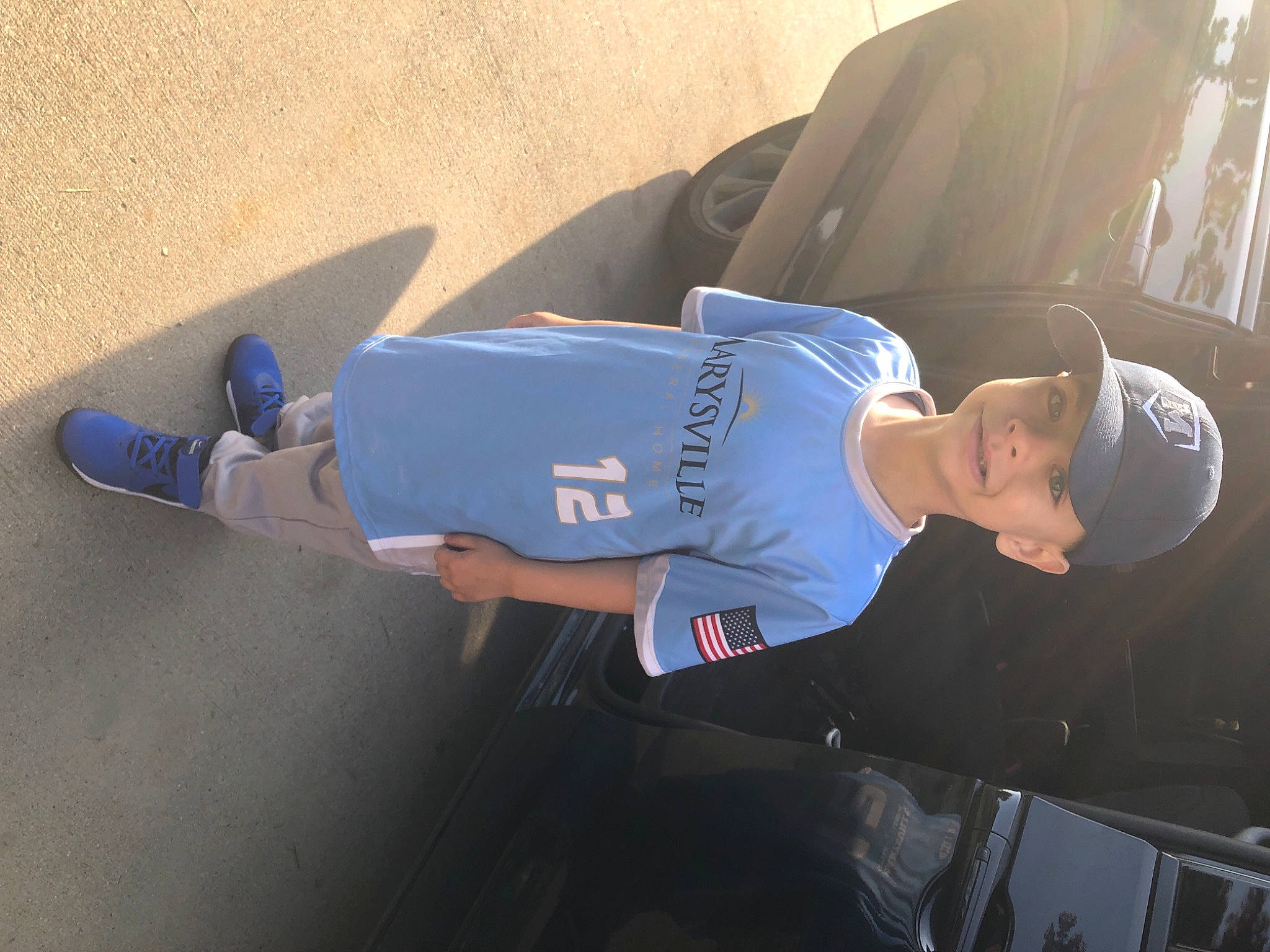 Devin is registered to the contest to win money with this photo: automotive_exterior, denim, elbow, electric_blue, family_car, fun, hat, headwear, human_leg, jeans, joint, knee, leg, person, shorts, sitting, sleeve, t_shirt, thigh, vehicle_door