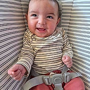 Ansley joined the competition — help win amazing prizes! baby, smiling, child, infant, seatbelt, striped_clothing, striped_background, happy, person, cute, indoors, sitting, clothing, baby_seat, pink_pants, face, head, hands, young_child, portrait