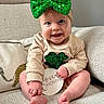 baby, infant, smiling, green_bow, sequin, four_months, couch, beige, clothing, cute, headband, shamrock, holding, sitting, happy, indoors, portrait, child, person, feet