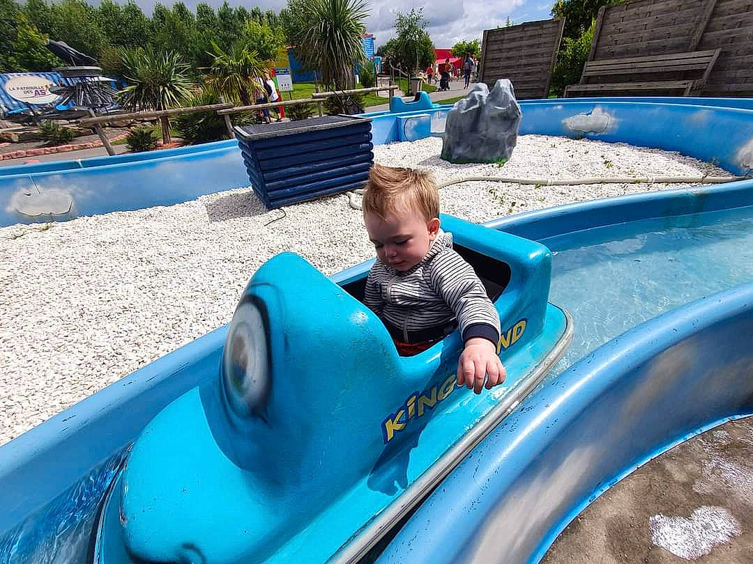 Bryan a rejoint le concours — aidez-le/la à gagner de superbes lots ! aqua, automotive_exterior, automotive_tire, automotive_wheel_system, azure, blue, bumper, chute, electric_blue, fun, leisure, motor_vehicle, outdoor_play_equipment, palm_tree, person, plant, playground, recreation, toddler, tree