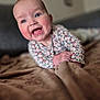 baby, smiling, blue_eyes, rosy_cheeks, blanket, hand, clothing, floral_pattern, face, expression, young_child, indoor, soft_texture, portrait, cute, happy, lying_down, infant, skin, closeup