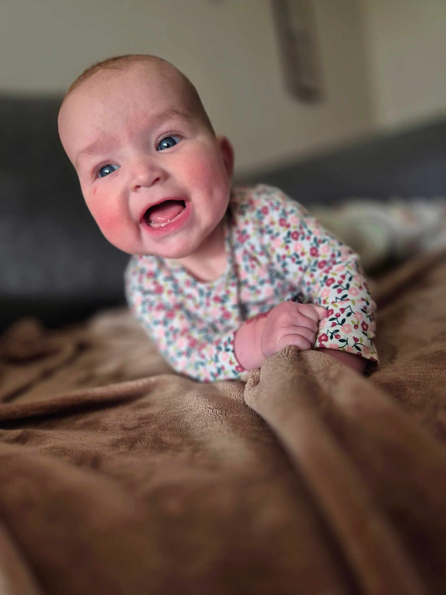 Emy participe au concours pour gagner de l'argent avec cette photo : baby, smiling, blue_eyes, rosy_cheeks, blanket, hand, clothing, floral_pattern, face, expression, young_child, indoor, soft_texture, portrait, cute, happy, lying_down, infant, skin, closeup