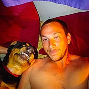 Sully Maynes joined the competition — help win amazing prizes! man, dog, bed, pillow, smile, shirtless, indoor, face, pet, canine, resting, curtain, purple, red, happy, lying_down, cozy, casual, portrait, friendship