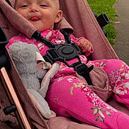 Ava joined the competition — help win amazing prizes! baby, child, stroller, pink_clothing, plush_toy, outdoor, park, tongue_out, happy, seatbelt, infant, grass, pathway, cute, person, smiling, nature, relaxed, casual, baby_girl