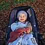 autumn, baby, beanie, blanket, child, clothing, cute, fall, happy, leaves, nature, outdoor, pacifier, park, person, seat, smile, stroller, toy, warm