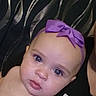 adult, baby, black_background, blanket, blue_eyes, calm, child, close_up, eyes, fabric, face, headband, indoor, infant, looking_at_camera, partial_face, photograph, portrait, purple_bow, skin