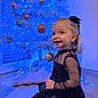 Luna participe au concours pour gagner de l'argent avec cette photo : child, toddler, christmas_tree, ornament, blue_lights, holiday, dress, smile, sitting, floor, decoration, bow, festive, indoor, portrait, sparkle, playful, tree_skirt, fairy_lights, wonder