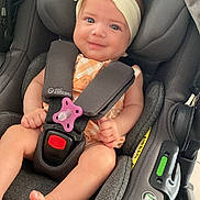 Alba a rejoint le concours — aidez-le/la à gagner de superbes lots ! baby, child, car_seat, infant, headband, pacifier, smiling, blue_eyes, orange_clothing, seatbelt, black_car_seat, safety, cute, indoor, person, toddler, foot, hand, portrait, happy
