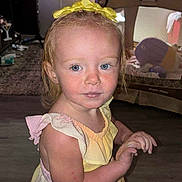 Renae joined the competition — help win amazing prizes! blue_eyes, child, curious, curtain, dress, floor, furniture, hair, hand, indoor, living_room, person, playpen, portrait, skin, toddler, toy, window, yellow_bow, young_child