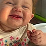 Aniyah is registered to the contest to win money with this photo: baby, child, close_up, curly_hair, cute, face, floral_pattern, food, hand, happy, high_chair, indoor, infant, person, rosy_cheeks, shirt, skin, smile, teeth, tongue