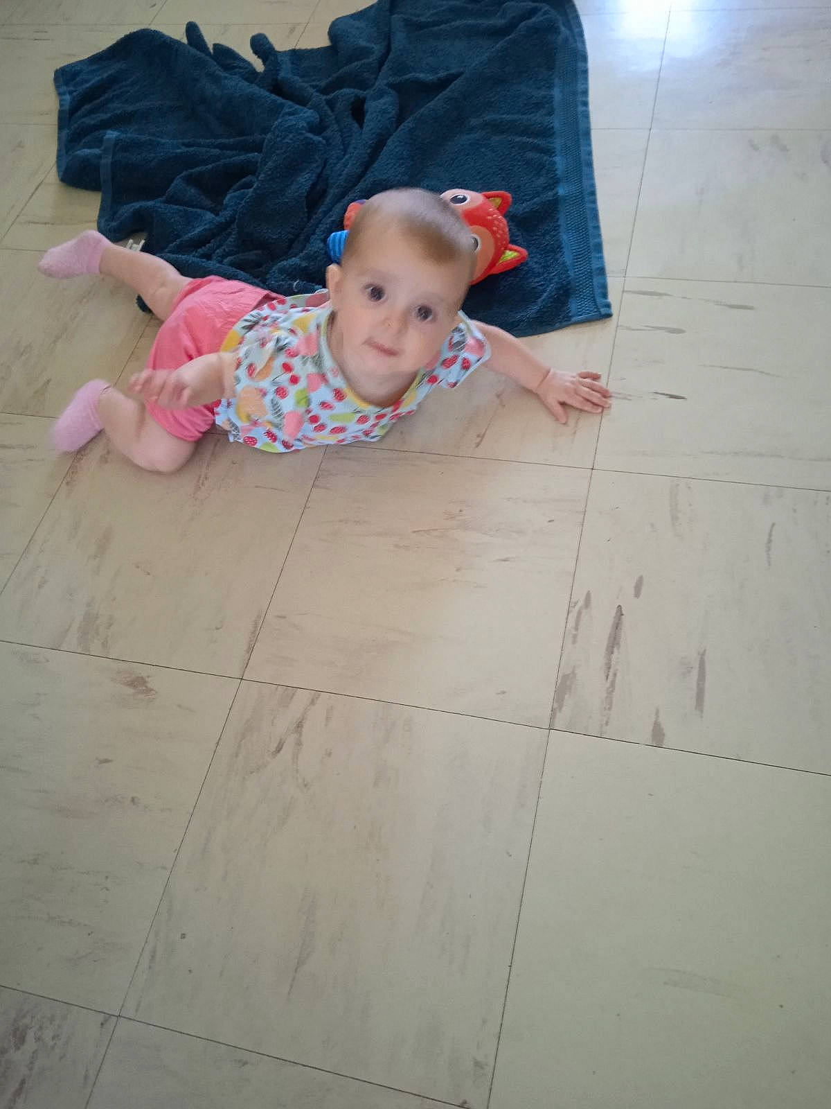 Clarisse participe au concours pour gagner de l'argent avec cette photo : baby, baby_toddler_clothing, cheek, child, concrete, eye, floor, flooring, fun, happy, hardwood, pattern, person, play, road_surface, sitting, skin, sleeve, t_shirt, toddler