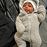 baby, infant, child, portrait, smiling, tongue_out, hat, onesie, fleece, teddy_bear, winter_clothing, lying_down, bed, bedding, striped_blanket, indoor, cozy, face, happy, photography