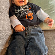Ryker is registered to the contest to win money with this photo: baby, child, smiling, jeans, tshirt, couch, cushion, indoor, person, happy, portrait, clothing, face, infant, sitting, cozy, casual, cute, young, relaxing