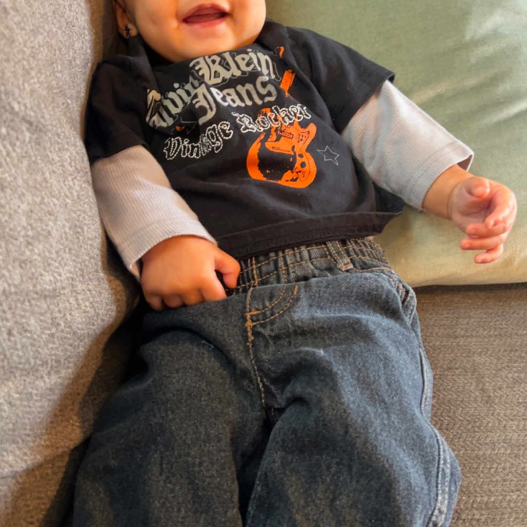 Ryker is registered to the contest to win money with this photo: baby, casual, child, clothing, couch, cozy, cushion, cute, face, happy, indoor, infant, jeans, person, portrait, relaxing, sitting, smiling, tshirt, young