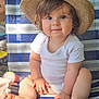 baby, child, hat, onesie, striped_chair, outdoor, smiling, cute, barefoot, toddler, sunlight, portrait, sitting, happy, skin, hand, foot, face, hair, person