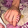 Marceau participe au concours pour gagner de l'argent avec cette photo : baby, adult_hand, baby_hand, skin, fingers, grip, touch, blanket, pattern, purple, yellow, white, comfort, connection, protection, closeup, human, bed, rest, love