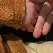 Marceau a rejoint le concours — aidez-le/la à gagner de superbes lots ! baby_hand, adult_hand, holding, brown_clothing, beige_clothing, close_up, skin, texture, soft_fabric, intimacy, connection, fingers, warm_colors, tender_moment, human_skin, child, parent, love, care, touch