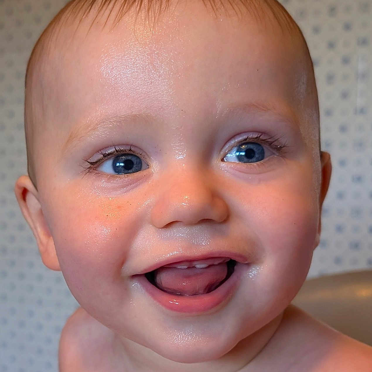 Charly participe au concours pour gagner de l'argent avec cette photo : baby, background, blue_eyes, child, close_up, cute, expression, face, happy, head, indoors, infant, joy, person, portrait, skin, smile, teeth, tongue, wet_skin